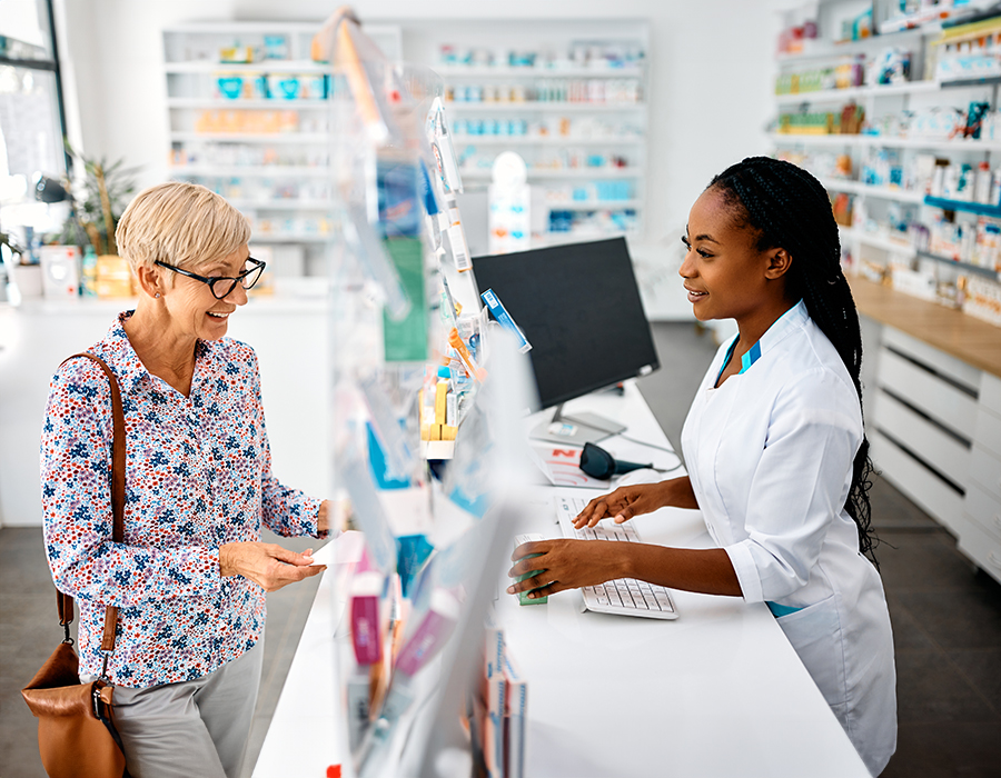 senior picking up prescription from pharmacist.